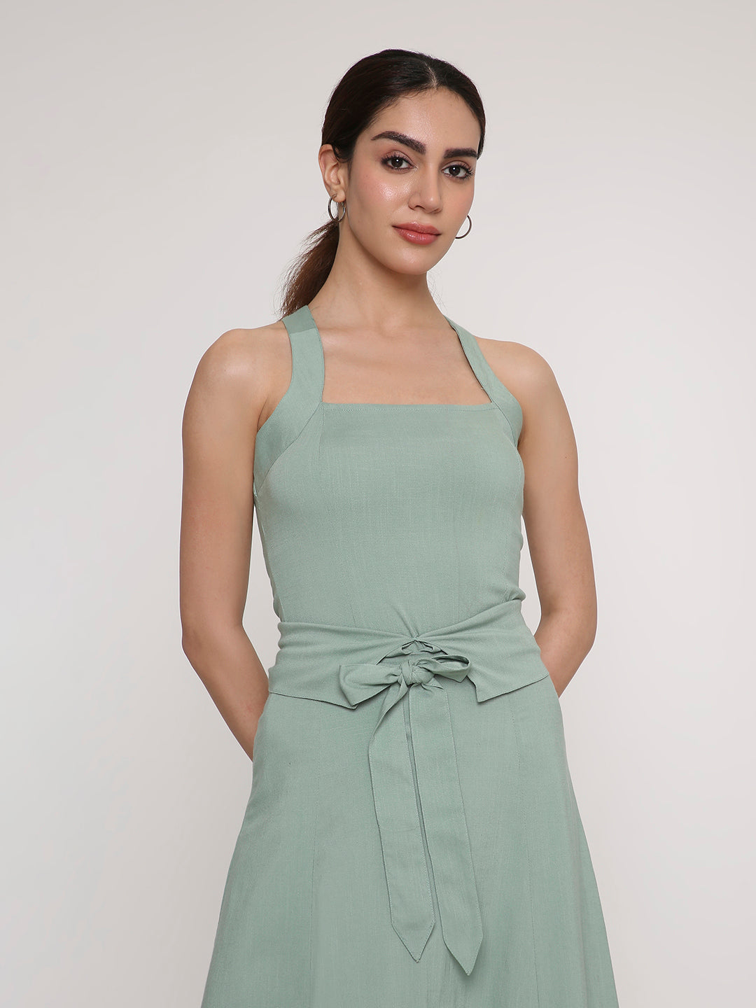 Woman wearing a sage green cross-back sleeveless halter top